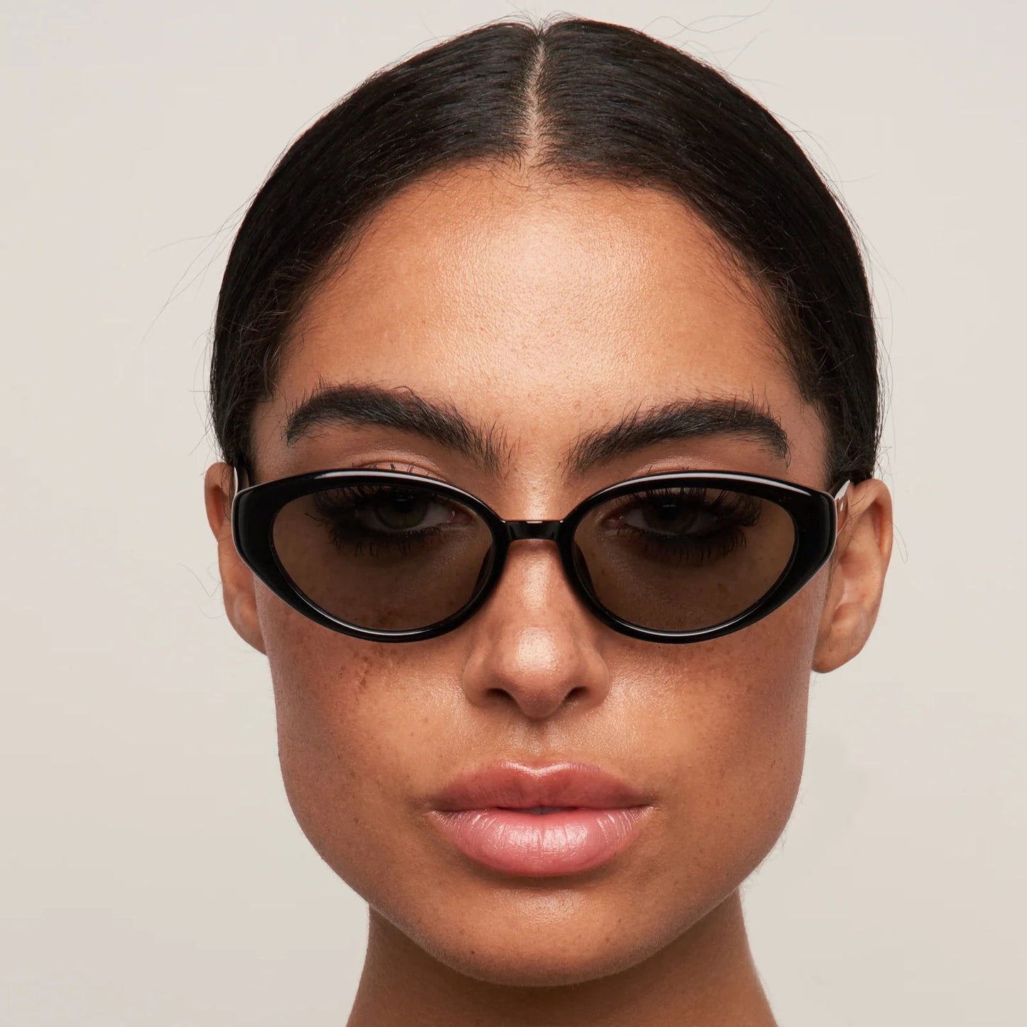 Person wearing black sunglasses with a neutral background