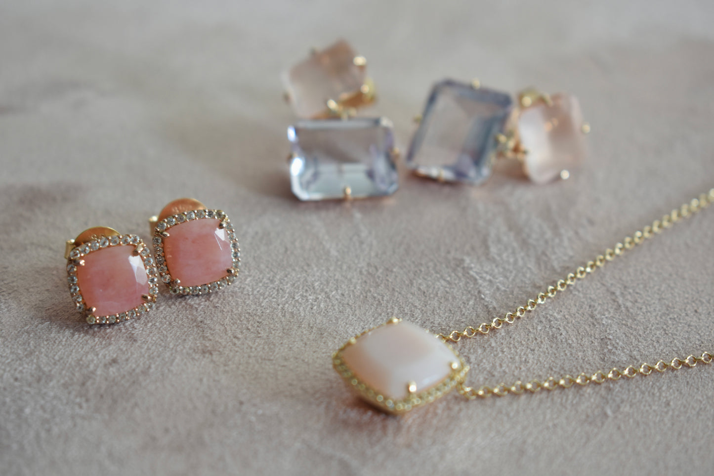 Jewelry set with pink stone necklace and earrings on a neutral background
