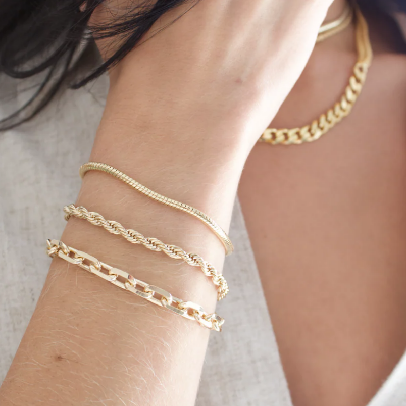 Gold chain bracelets on a wrist with a blurred background