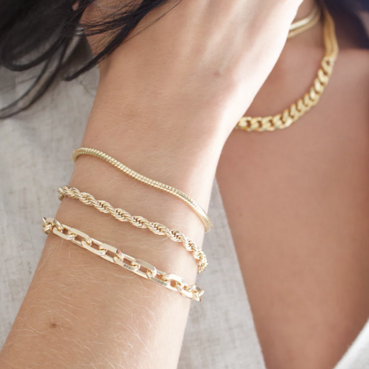 Gold chain bracelets on a wrist with a blurred background
