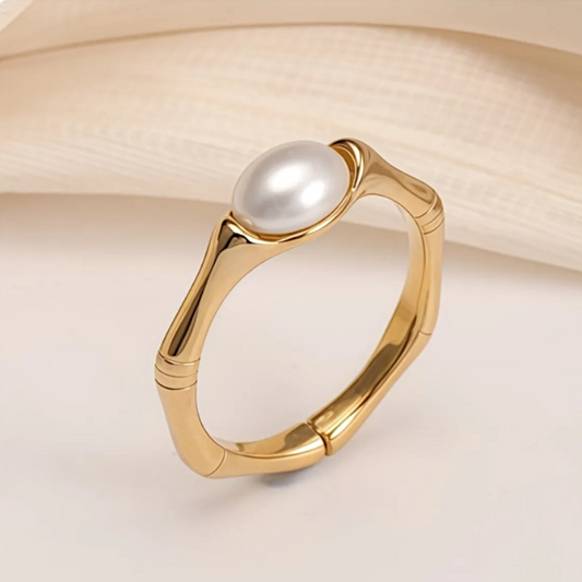 Gold ring with a pearl on a light beige background