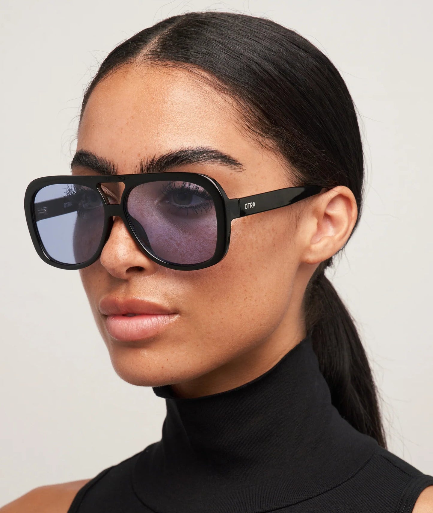 Woman wearing black sunglasses with a plain background