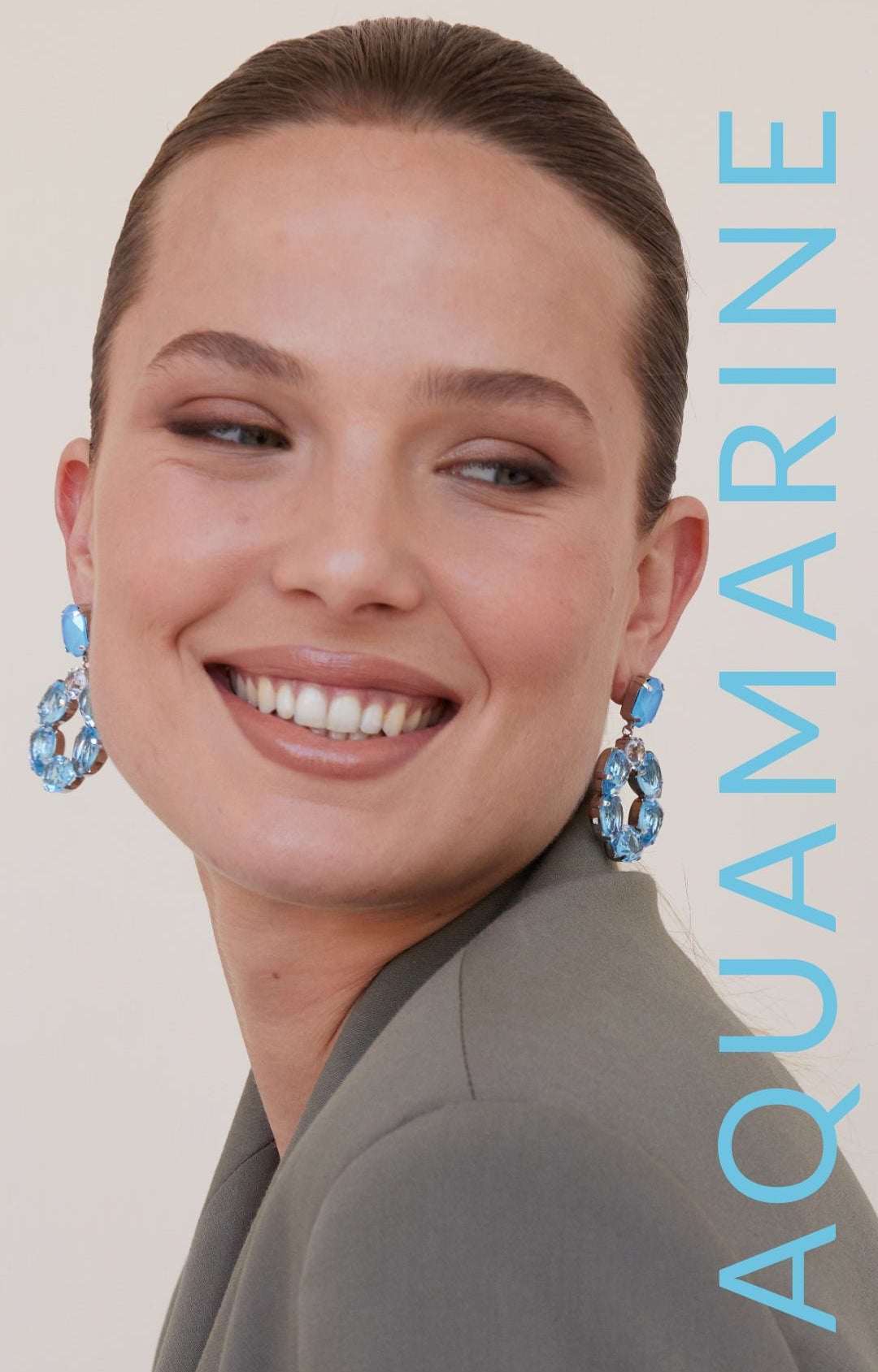 Woman wearing blue earrings with the word 'Aquamarine' on a beige background