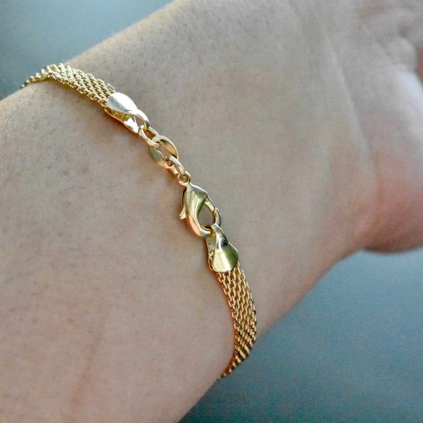 Gold bracelet on a wrist with a light background