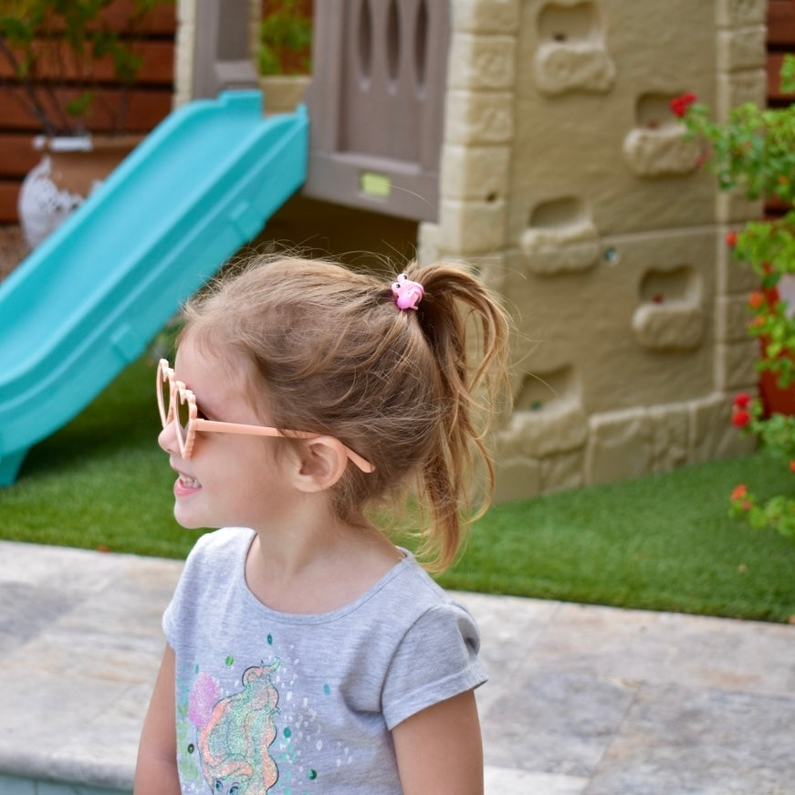 Child wearing sunglasses in front of a playground slide and climbing wall