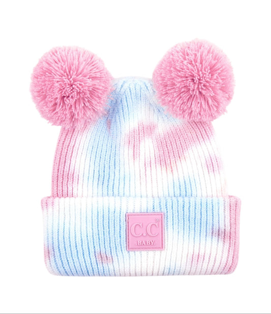 Tie-dye beanie with pink pom-poms and a visible brand logo on a white background