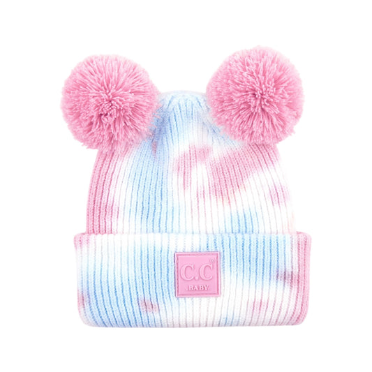 Tie-dye beanie with pink pom-poms and a visible brand logo on a white background