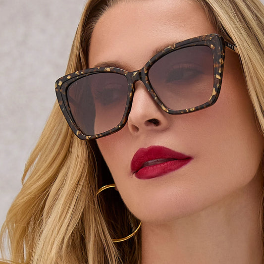 Close-up of a woman wearing tortoiseshell sunglasses with a neutral background