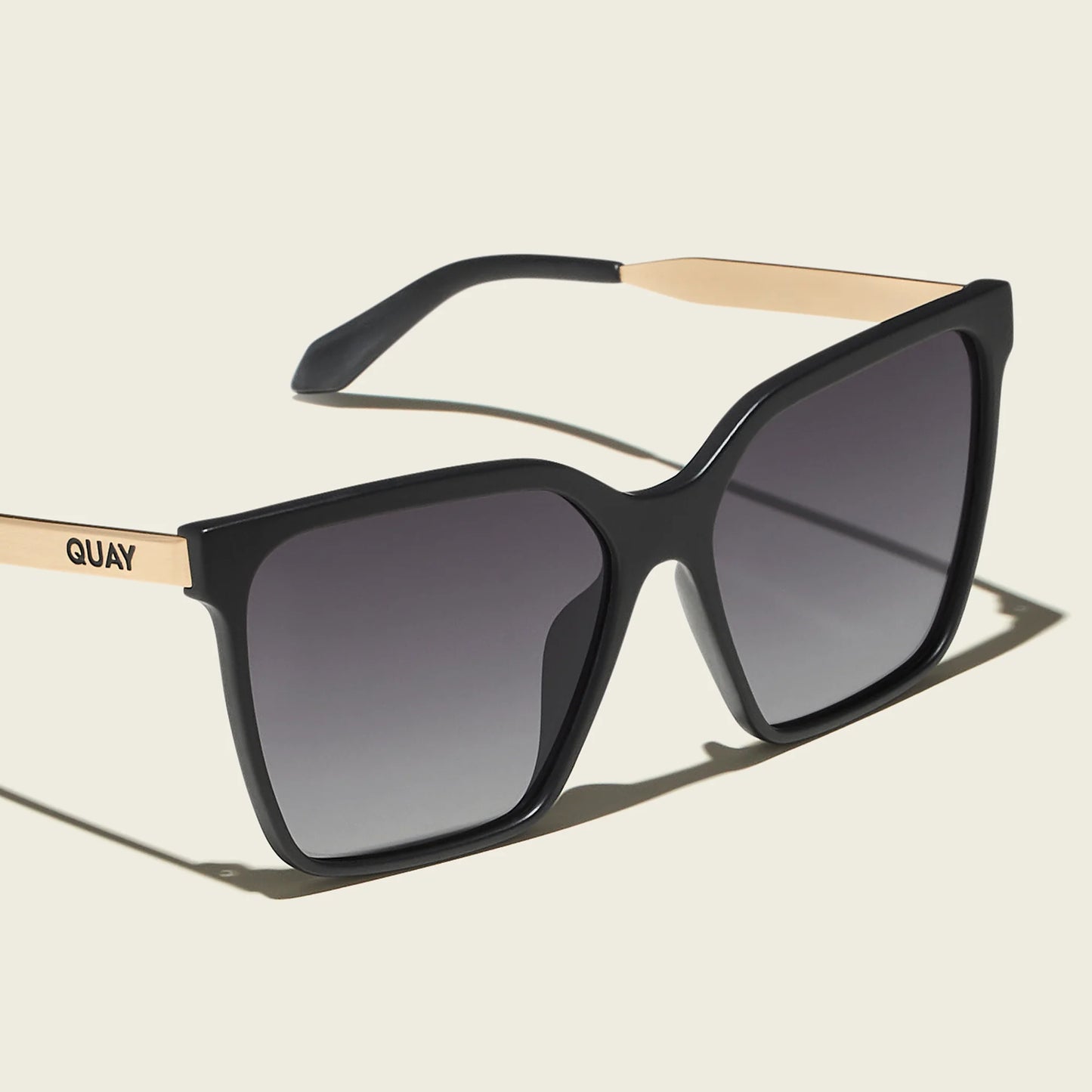 Black sunglasses with beige accents on a light beige background