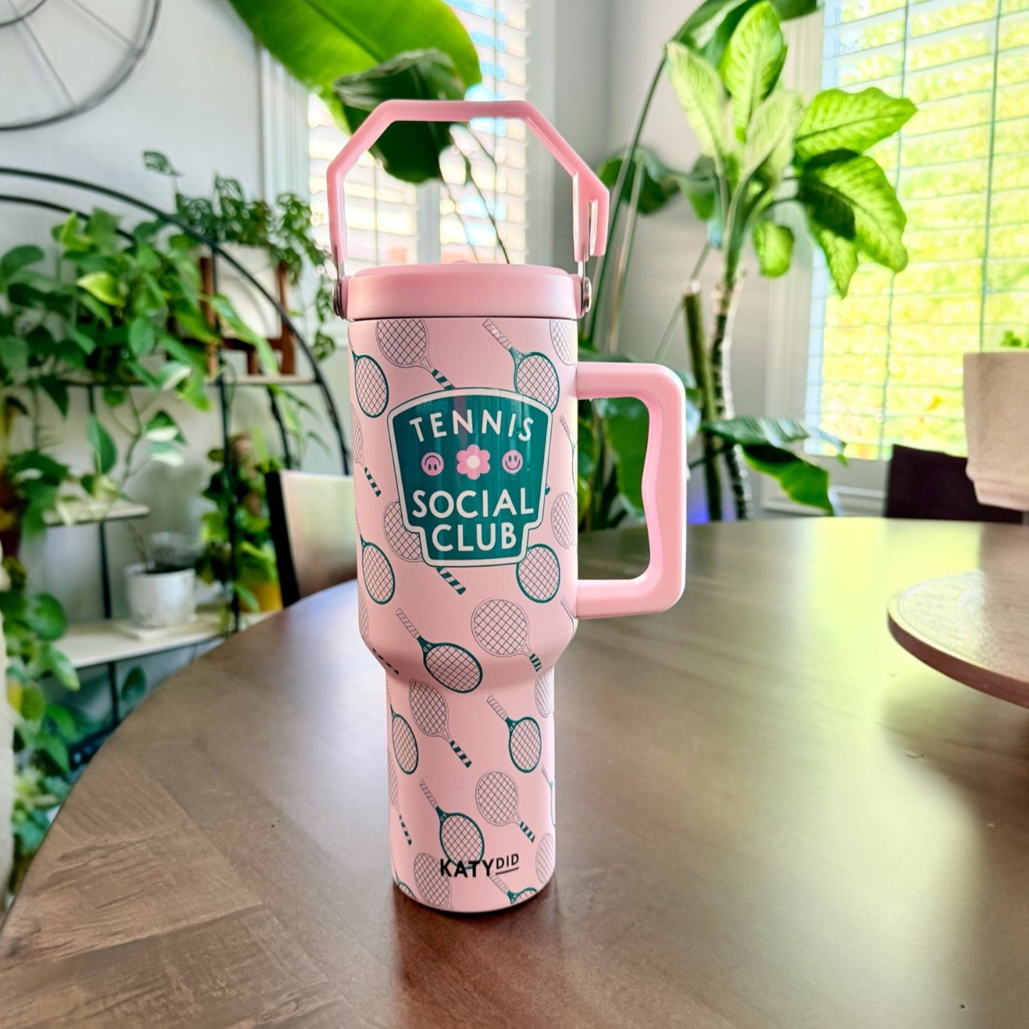 Pink and green tennis club tumbler on a brown table with plants behind it
38 ounces
includes reusable plastic straw
all-day chill or heat
