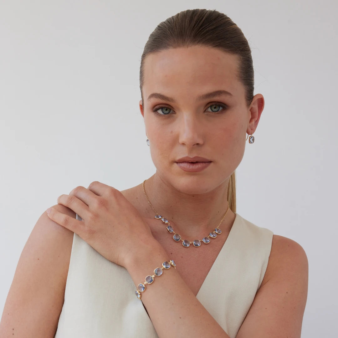 Woman wearing gold jewelry including a necklace and bracelet against a plain background
Material: 925 sterling silver, gold-plated, cushion cut translucent light Aquamarine Swarovski crystals
Color: gold, light blue
Measurement: 14" length, 1" extension, 1 mm wide chain