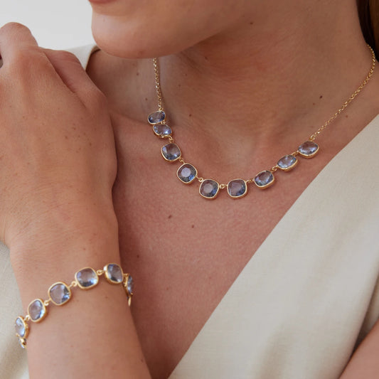 Gold necklace and bracelet with crystals on a person wearing a white top.
Material: 925 sterling silver, gold-plated, cushion cut translucent light Aquamarine Swarovski crystals
Color: gold, light blue
Measurement: 14" length, 1" extension, 1 mm wide chain