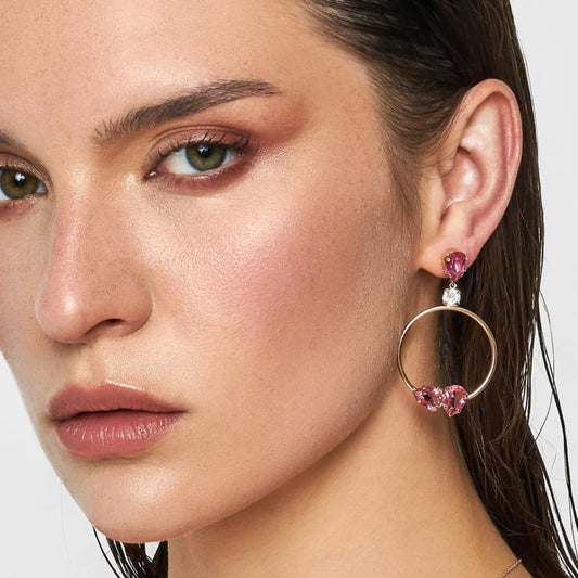 Close-up of a woman wearing pink hoop earrings with heart-shaped crystals.
Material: Sterling Silver, Rose Gold Plated, Swarovski Crystals
Color: sterling silver, rose gold, white, and pink
Measurement: 1 mm thickness, 5 cm length, 3 cm width