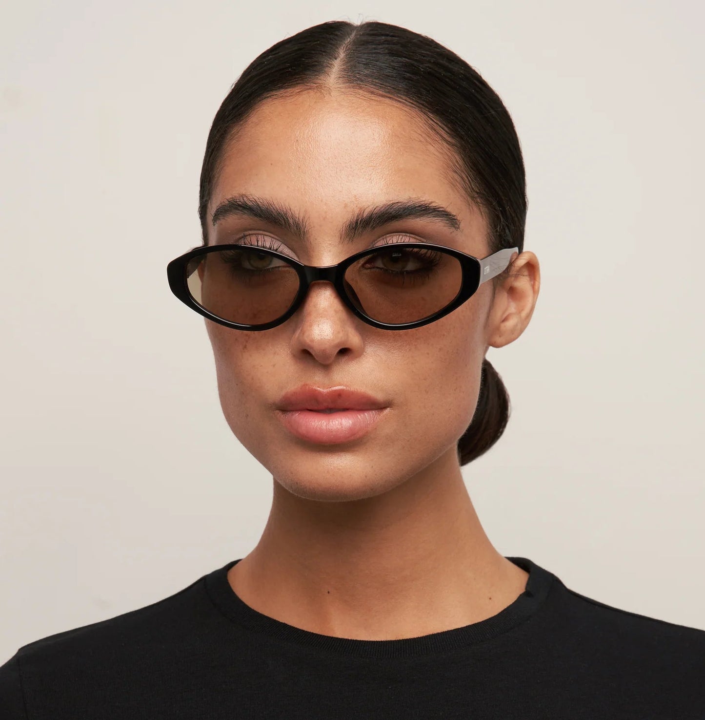 Woman wearing dark sunglasses against a plain background