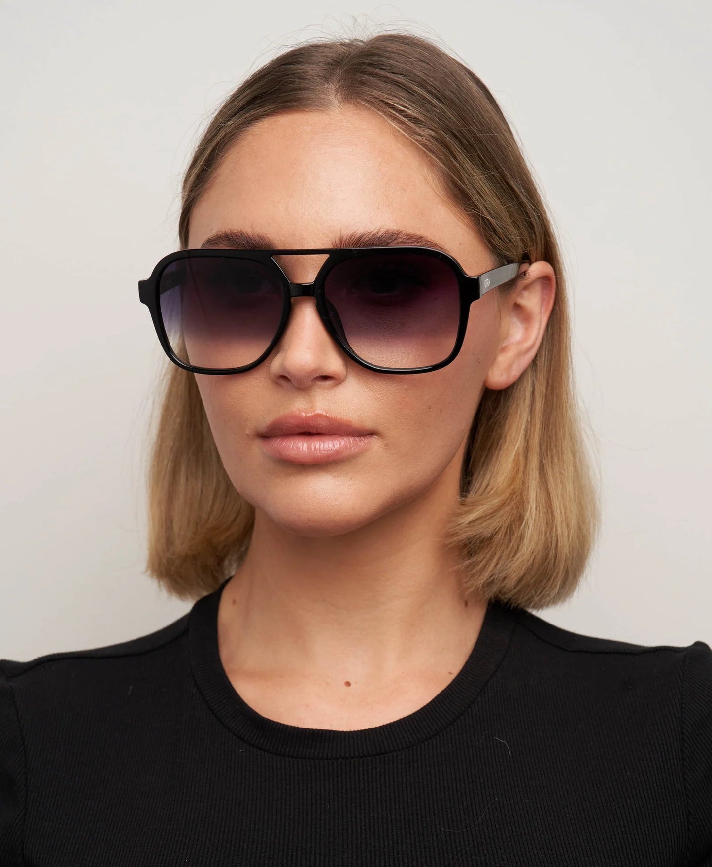 Woman wearing large sunglasses against a plain background