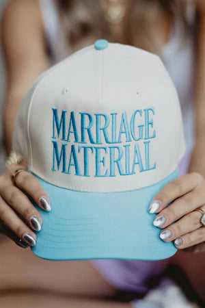 Cap with 'Marriage Material' text held by a person