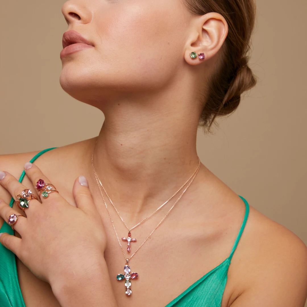 Woman wearing a necklaces, rings, and earrings with swarovski crystals on a beige background