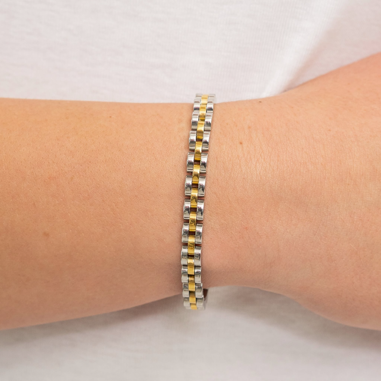 Gold watch band on a wrist with a plain background