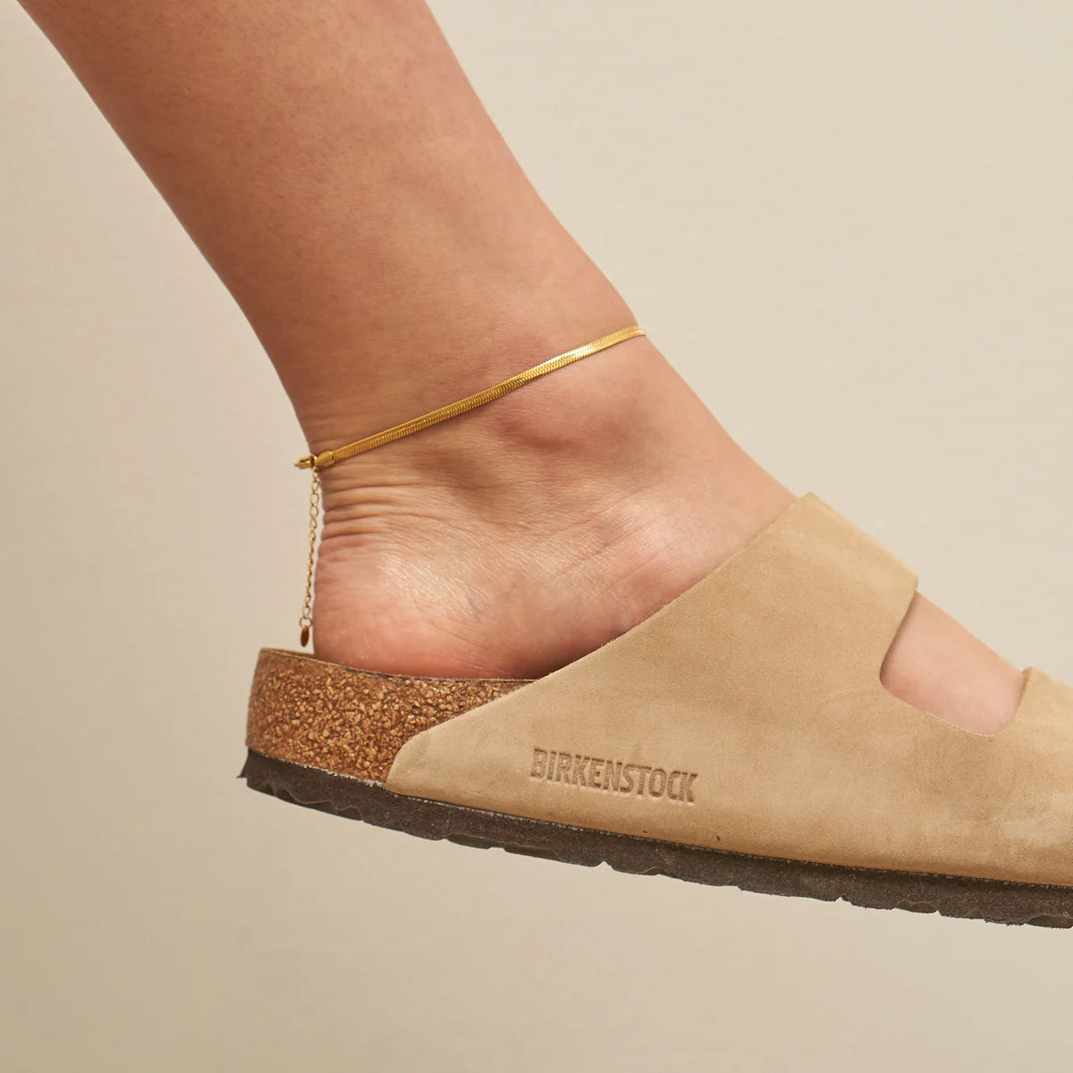 Beige sandal with 'Birkenstock' branding on a beige background