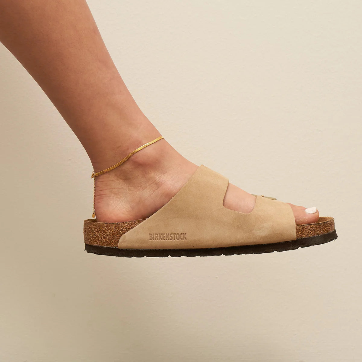 Beige sandal with 'Birkenstock' branding on a neutral background