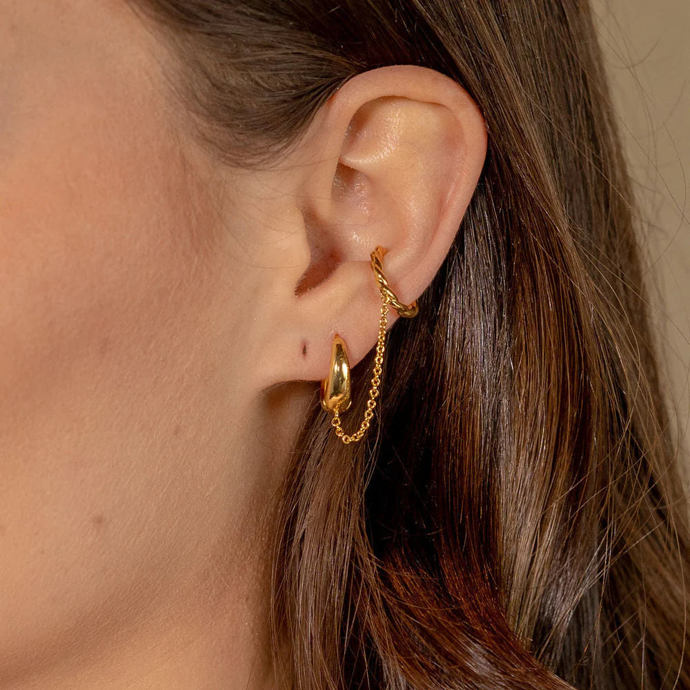 Gold hoop earrings worn by a person with brown hair.