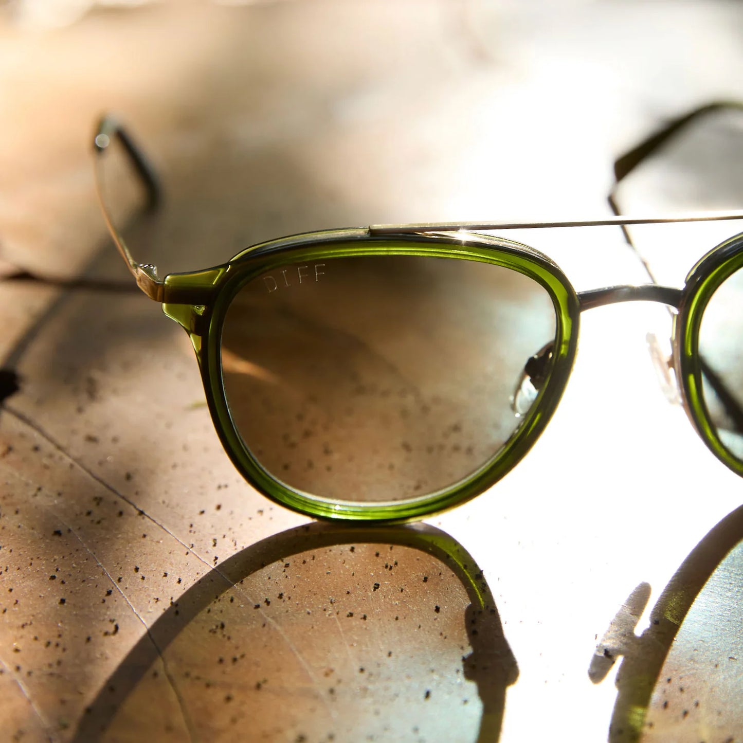 Green sunglasses with reflective lenses on a textured surface