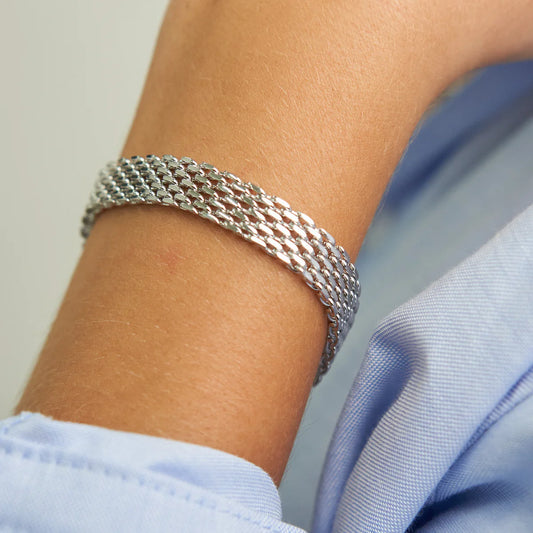 Silver bracelet on a wrist with a light blue shirt sleeve.
