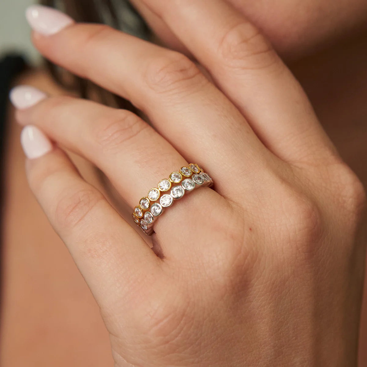 Close-up of a hand wearing a diamond ring with a blurred background