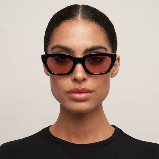 Person wearing black sunglasses with a neutral background