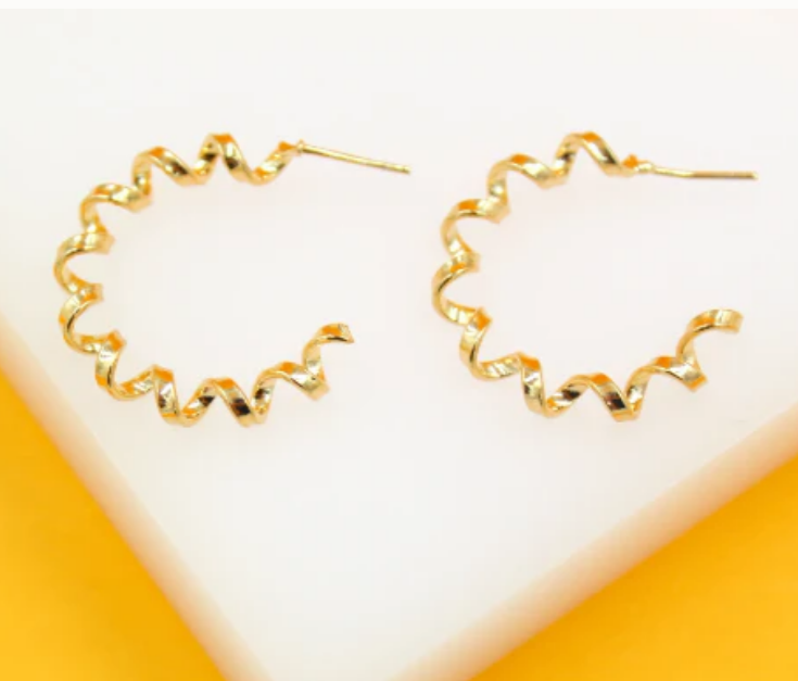 Gold spiral-shaped earrings on a white and orange background