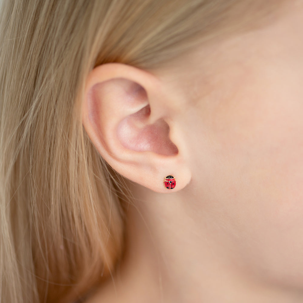 Age Group: Cute for Infants, Toddlers and Little Girls; Safe for Sensitive Ears
Material: 14k Yellow Gold
Earring Size: 5mm ladybug, enamel; 7mm threaded earring post
Color: Enamel
Metal Stamp: 14k
Ladybug earrings on the ear of a young girl.