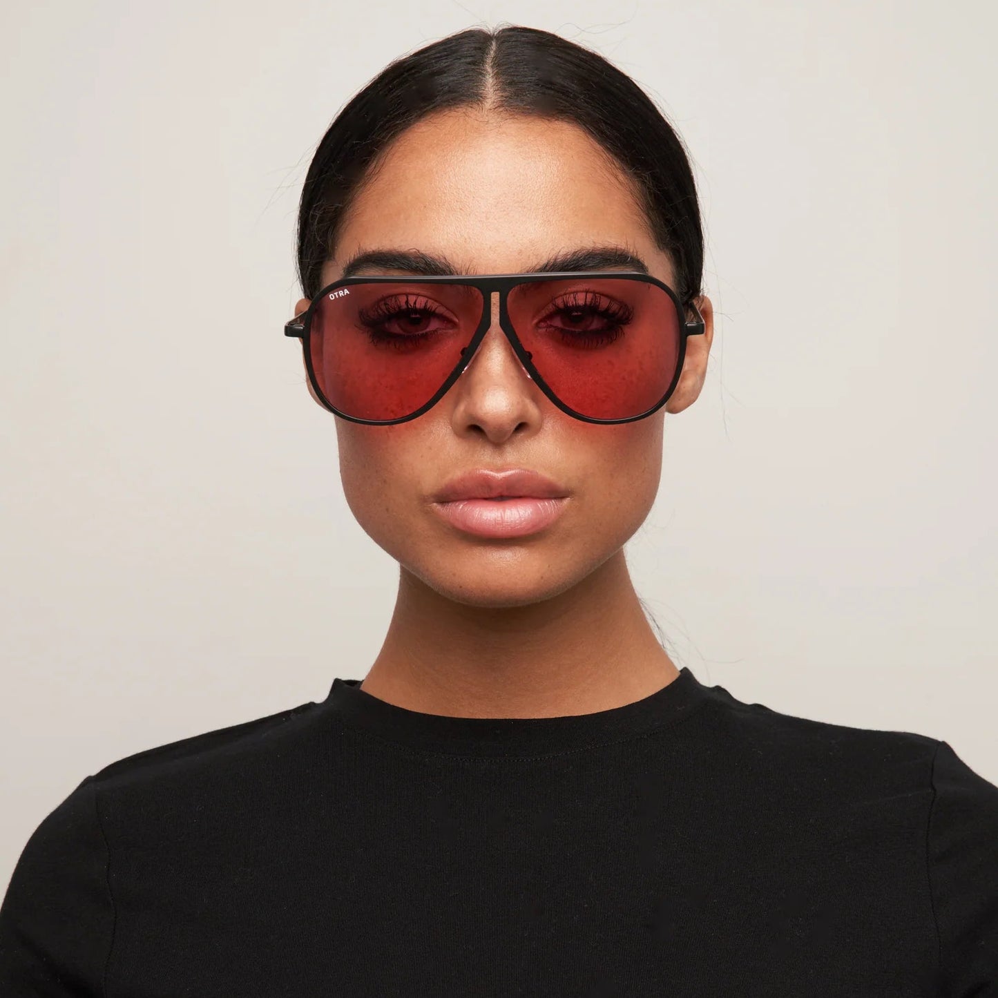 Person wearing a black t-shirt and red sunglasses against a plain background