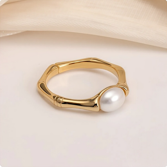 Gold ring with a pearl on a beige fabric background