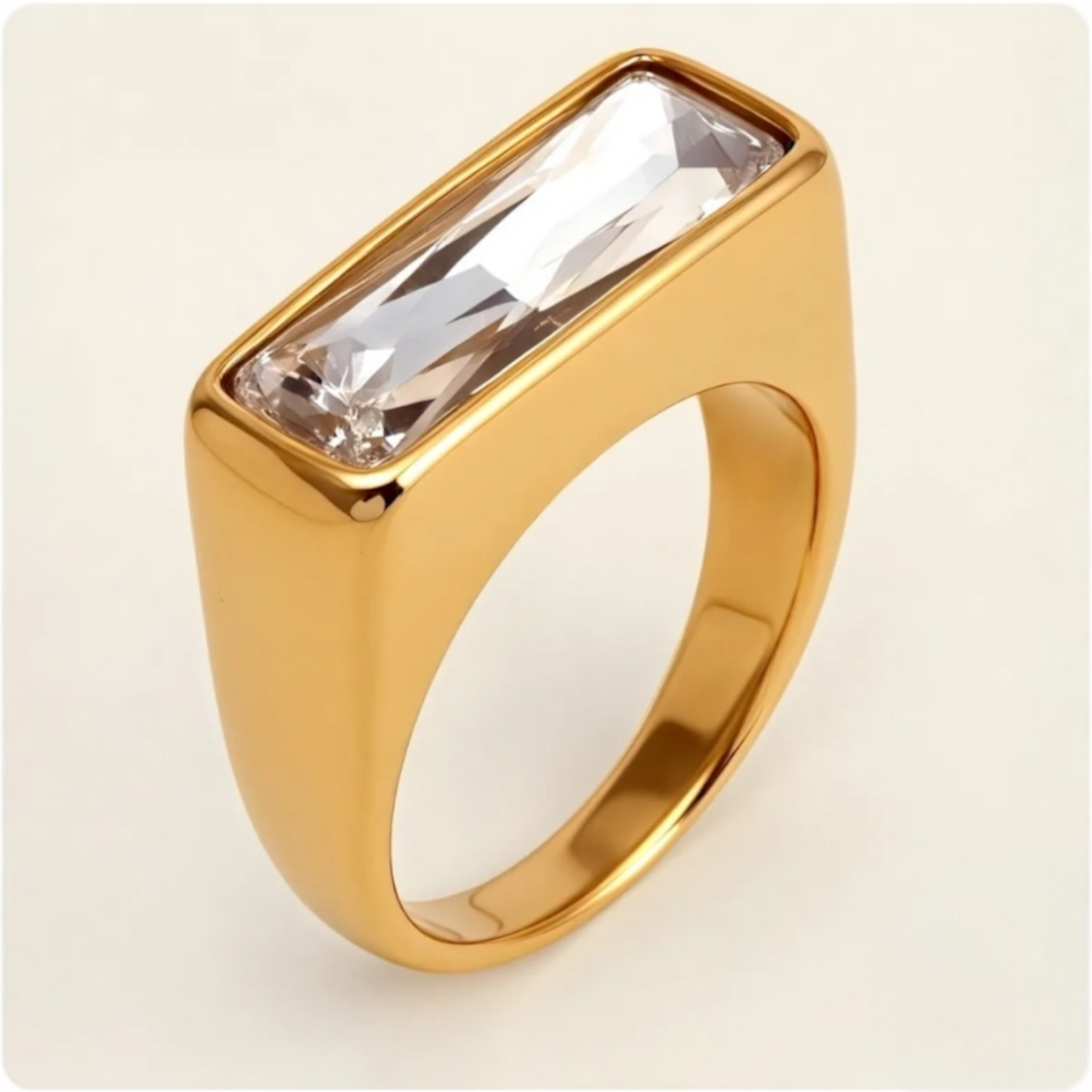 Gold ring with a rectangular crystal on a beige background