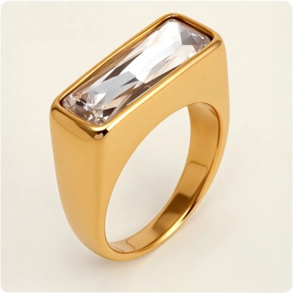 Gold ring with a rectangular crystal on a beige background