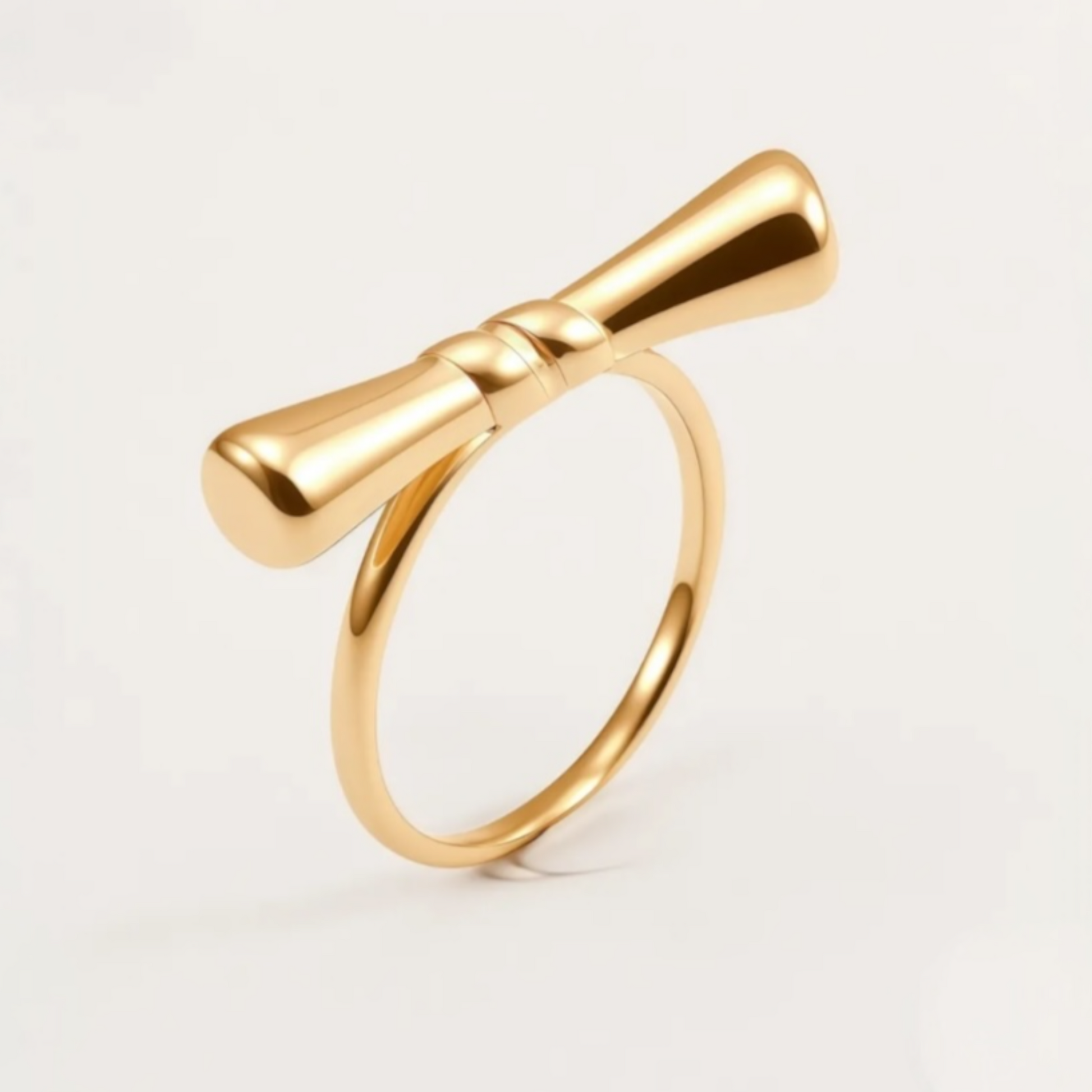 Gold bow-shaped ring on a light gray background