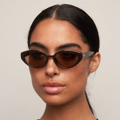 Woman wearing dark sunglasses against a plain background