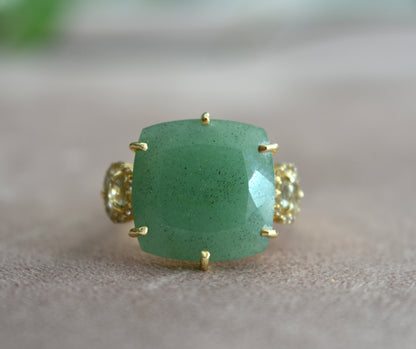 Green gemstone ring with gold accents on a neutral background