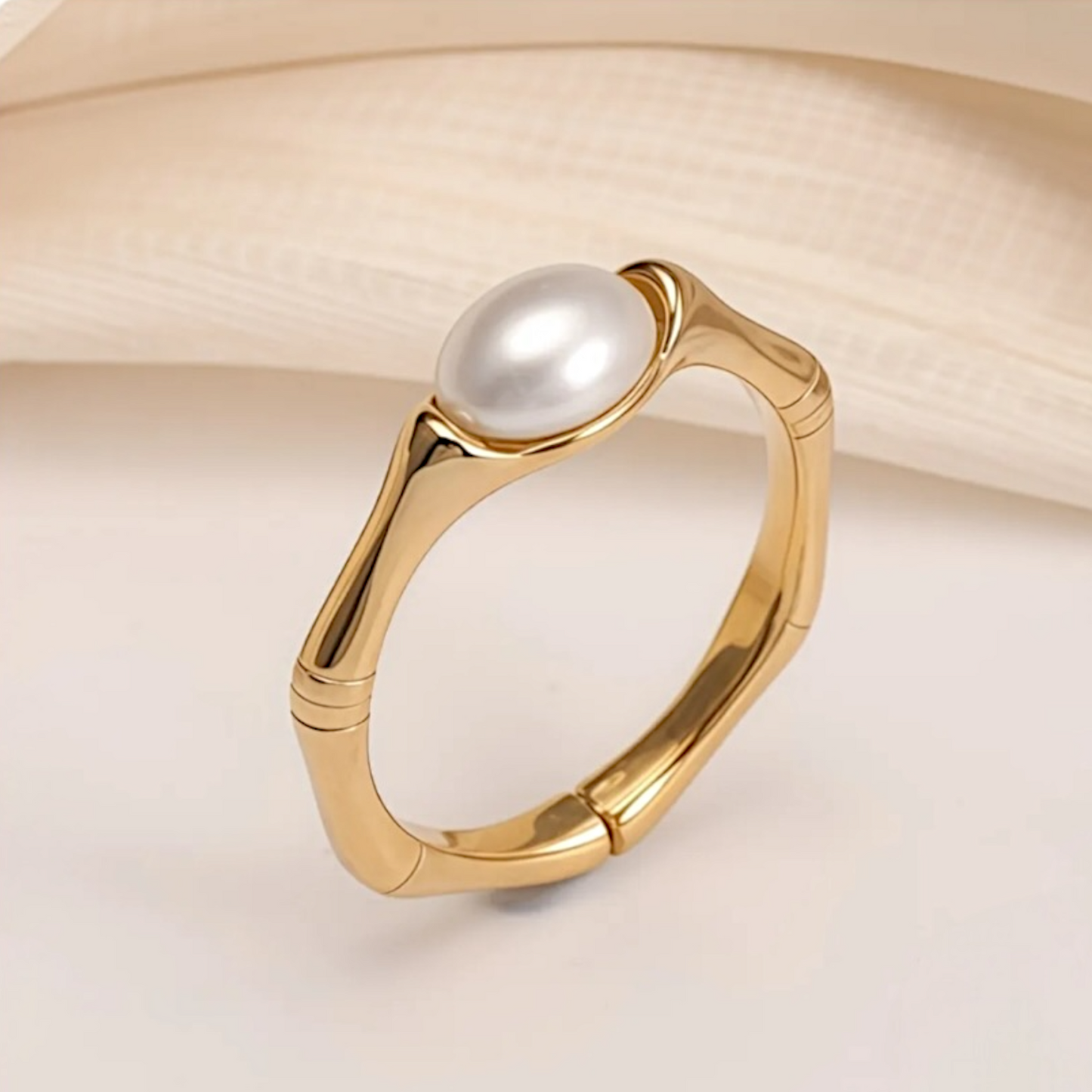 Gold ring with a pearl on a light beige background
