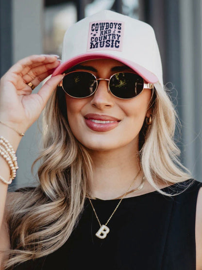 Woman wearing a pink cap with text and sunglasses, outdoors.