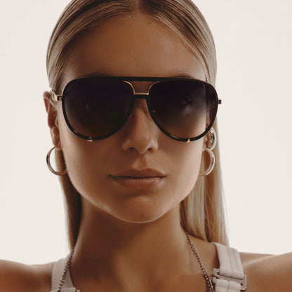 Close-up of a person wearing dark sunglasses with a neutral background