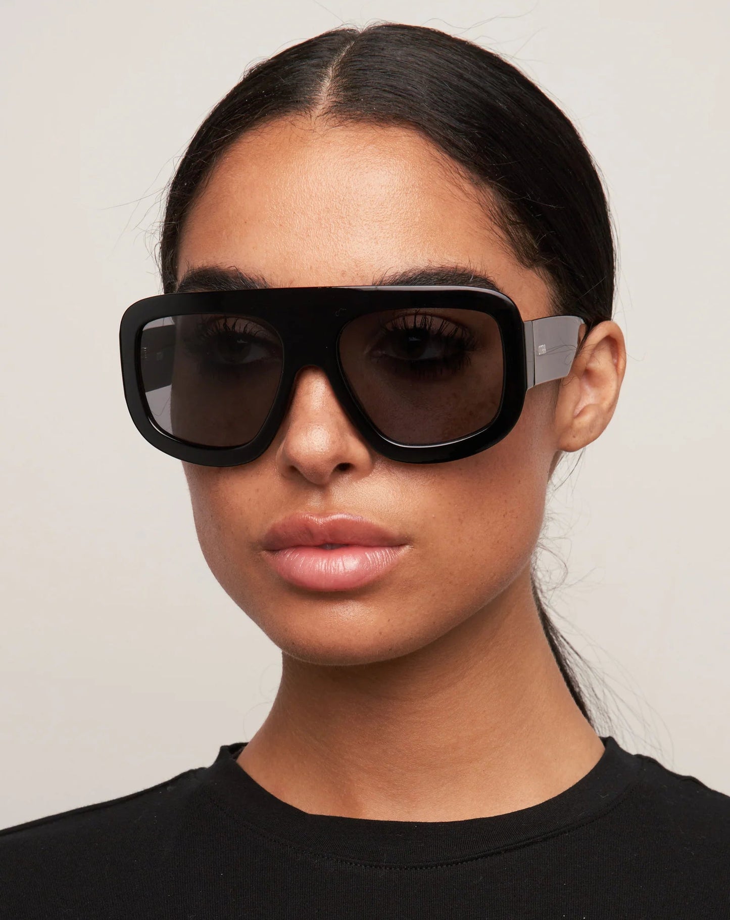 Woman wearing black sunglasses against a plain background