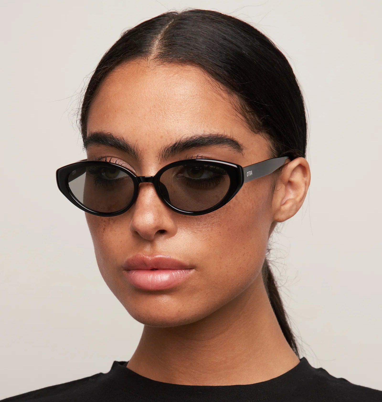 Woman wearing black sunglasses with a plain background