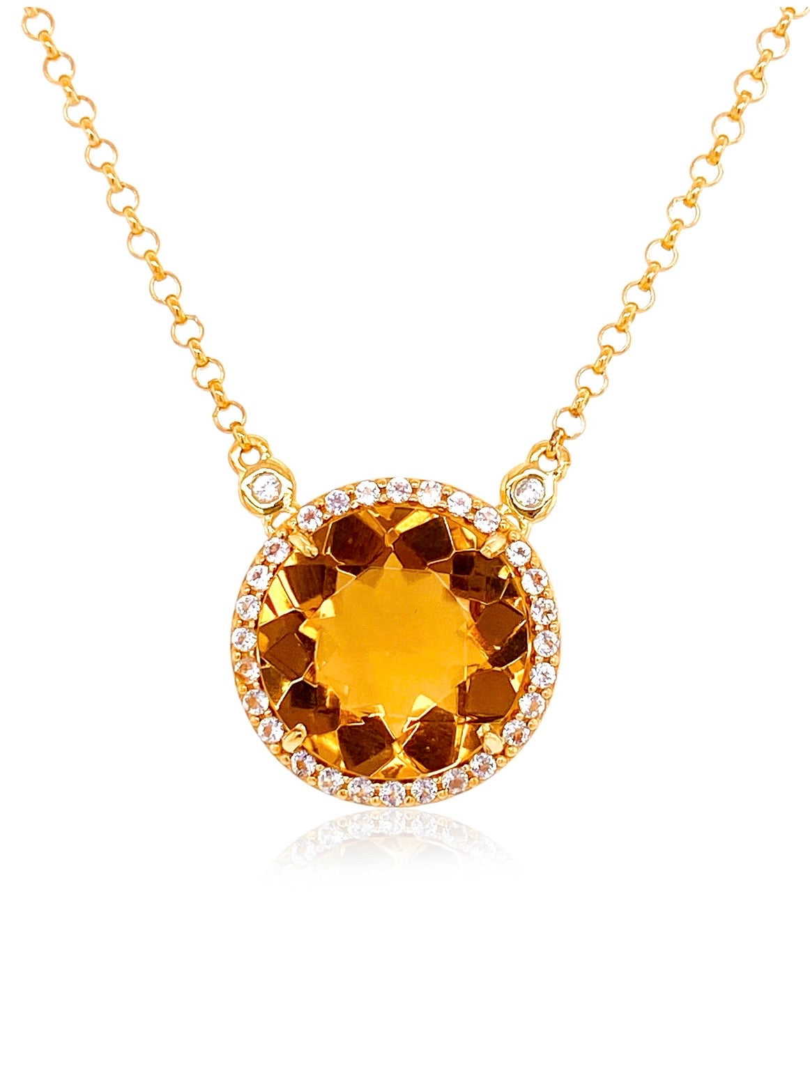 A gold pendant necklace featuring a large, round faceted orange-brown gemstone surrounded by a halo of small clear stones, suspended from a delicate gold chain on a white background.