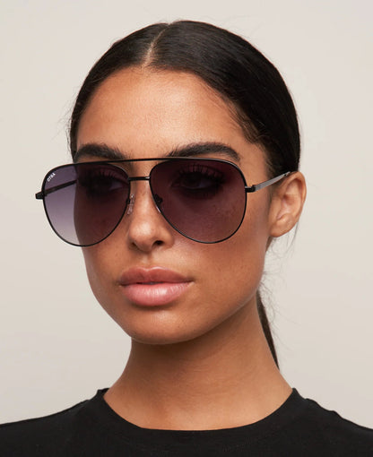 Woman wearing dark sunglasses against a plain background