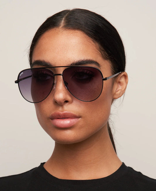 Woman wearing dark sunglasses against a plain background