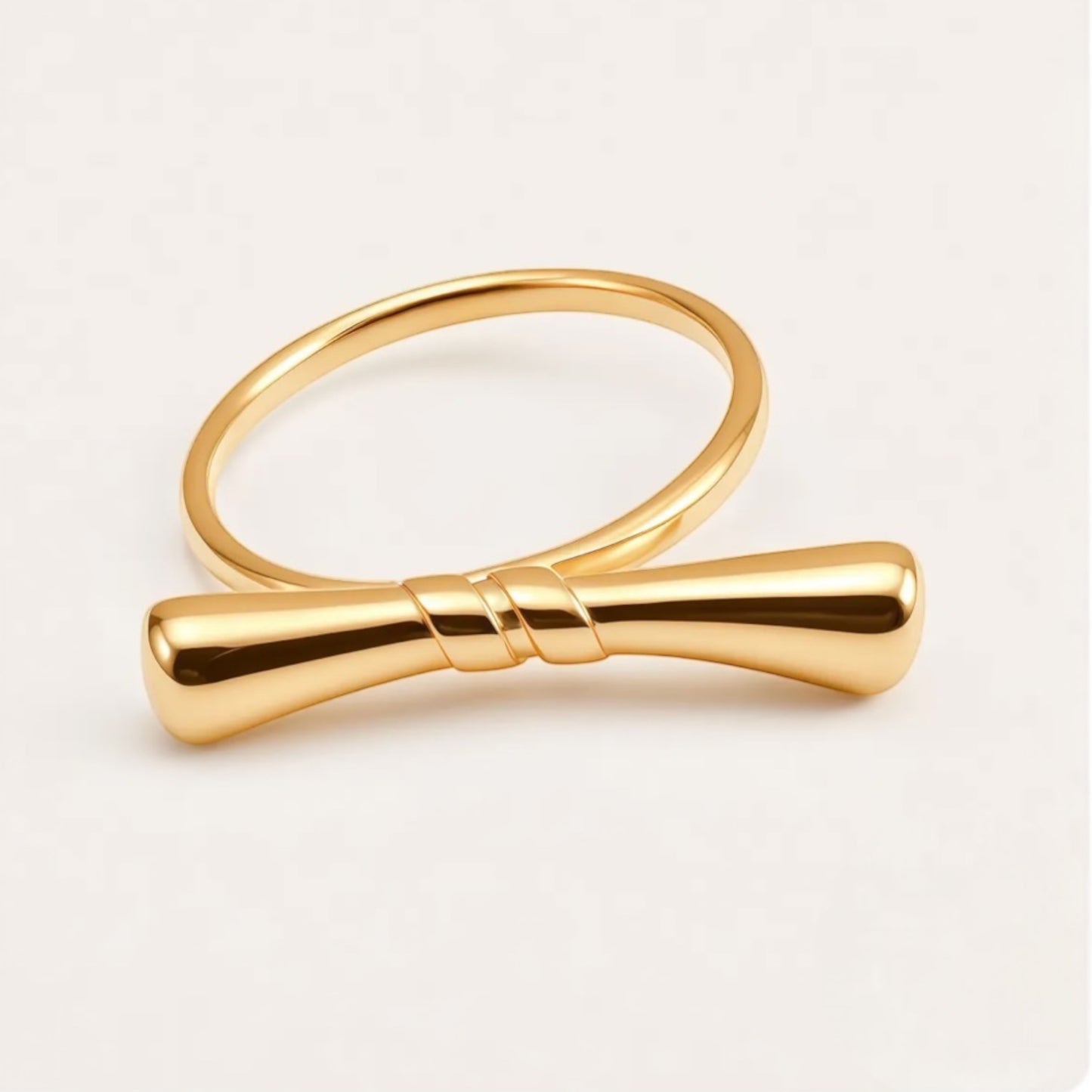 Gold bow-shaped ring on a light beige background