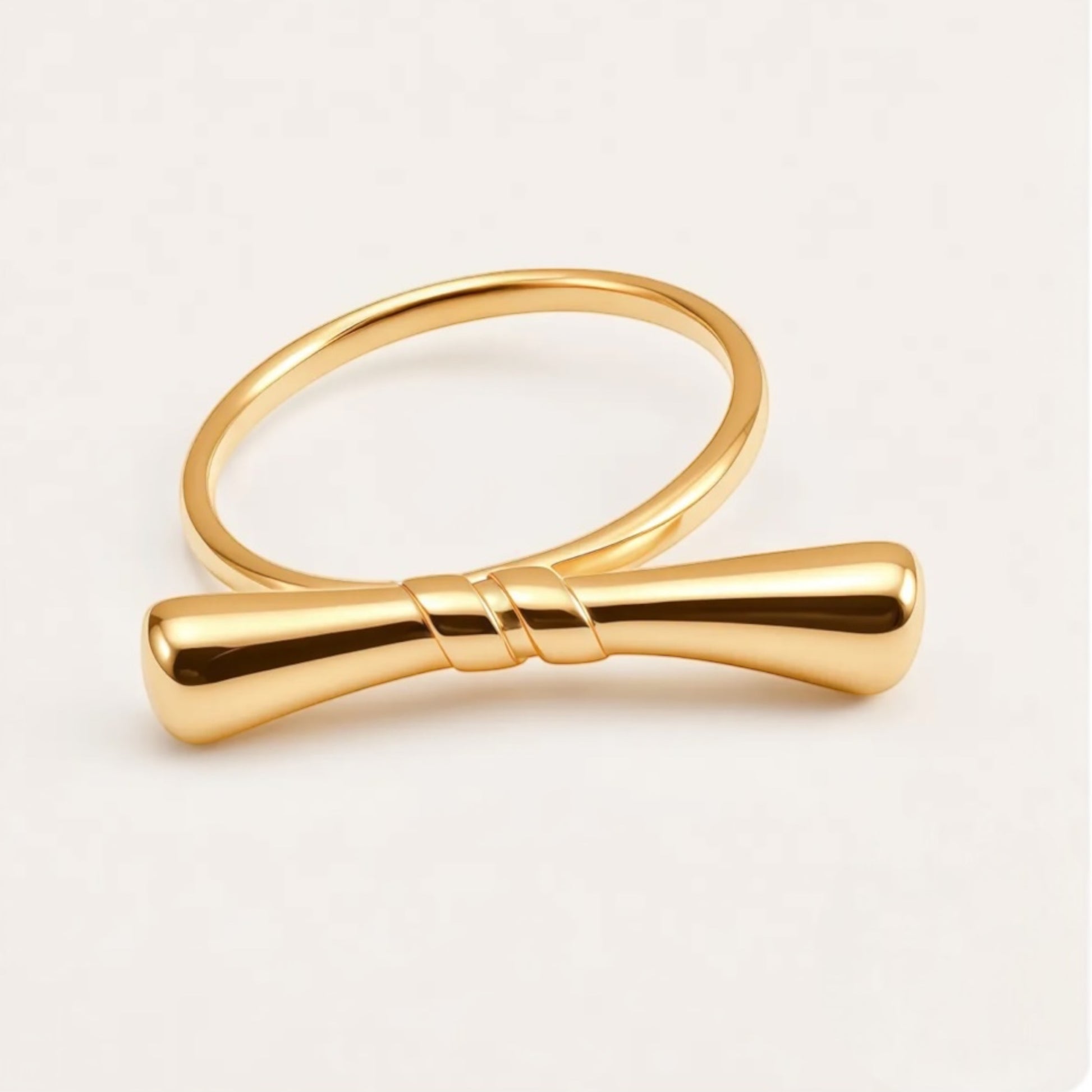 Gold bow-shaped ring on a light beige background