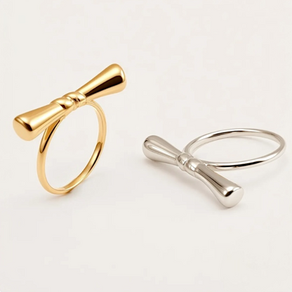 Gold and silver bow-shaped rings on a light gray background