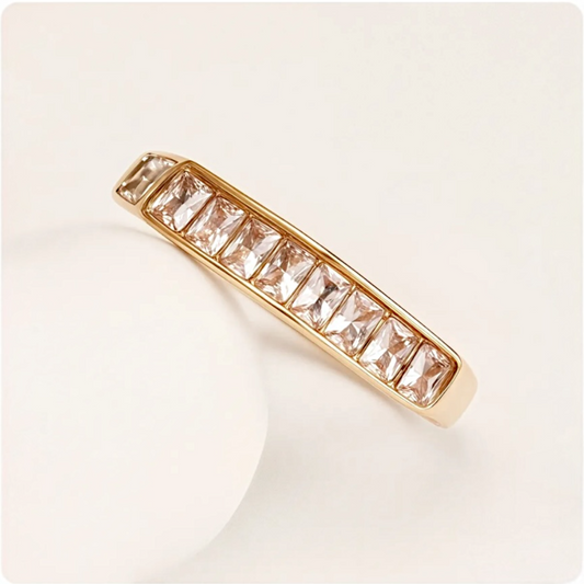 Gold ring with clear gemstones on a light beige background
